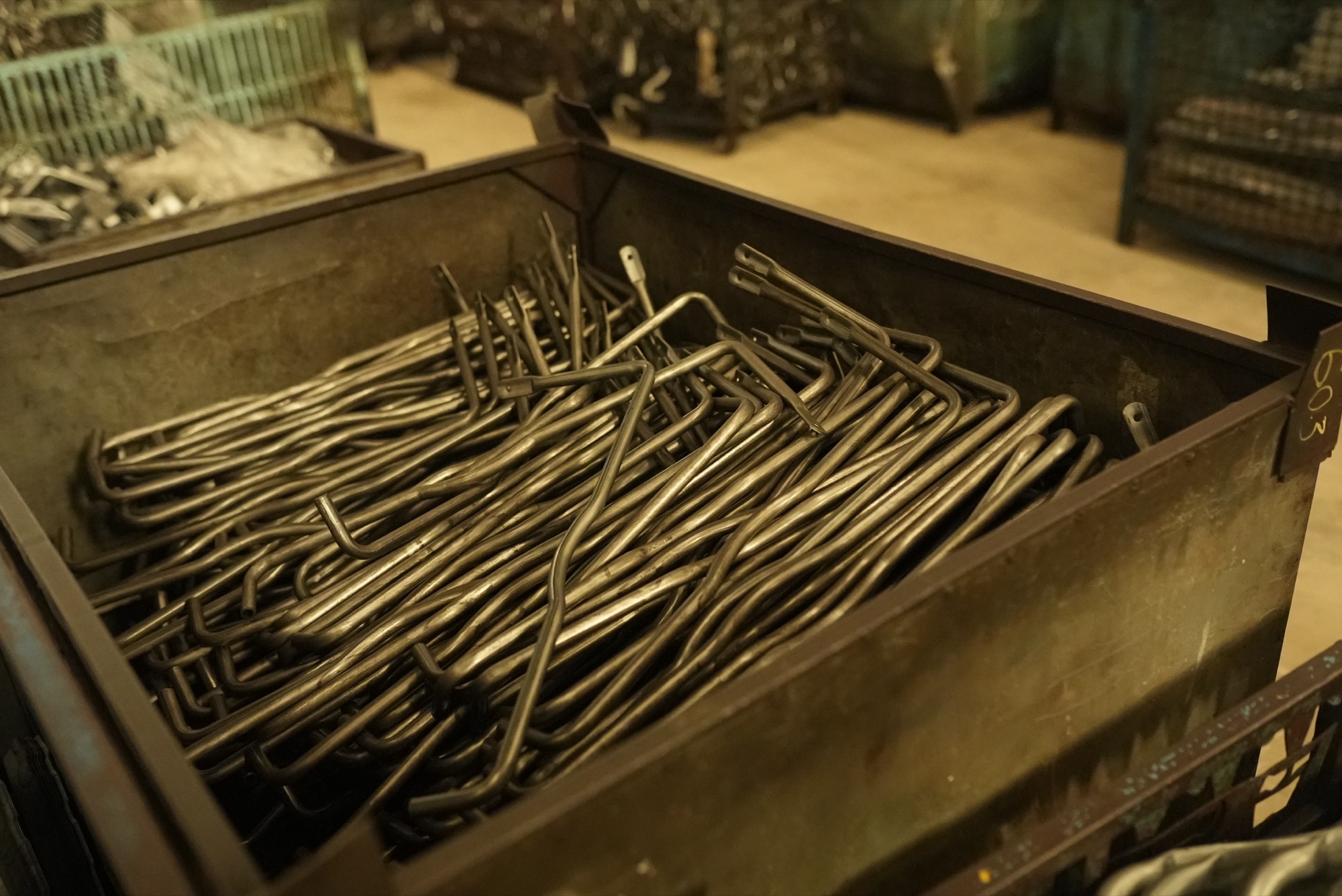 Steel bin filled with bent rod parts with flattened, pierced ends