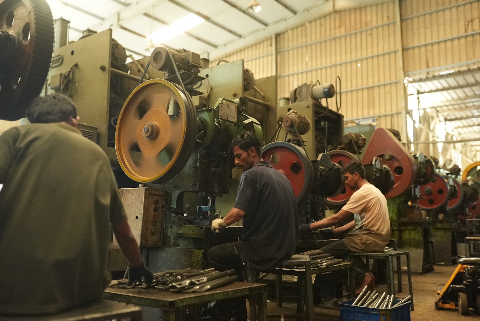 Three operators working side by side at a row of power presses