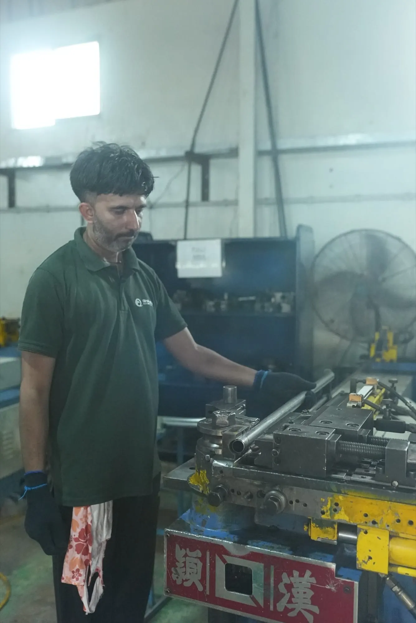 Operator placing a steel tube into a hydraulic pipe bending machine
