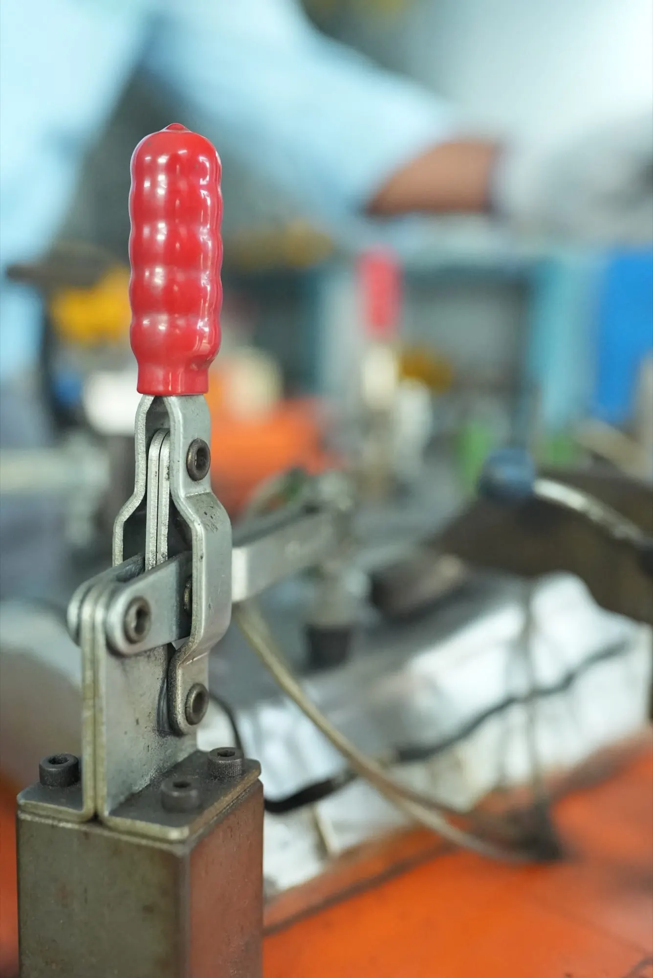 Close-up of a red-handled toggle clamp on a checking fixture